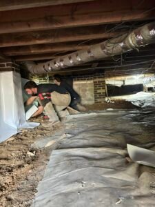 plumbers working on vapor barrier installation