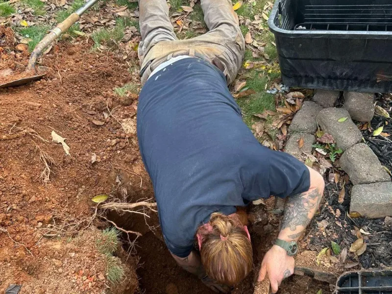 Plumber digging by hand to reach a water line