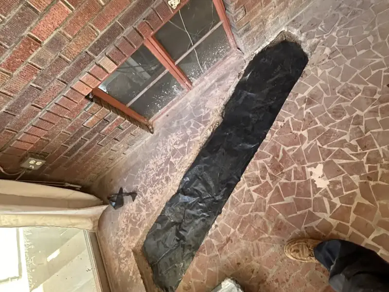Floor trench for a rerouted drain line, sealed before the slab patch