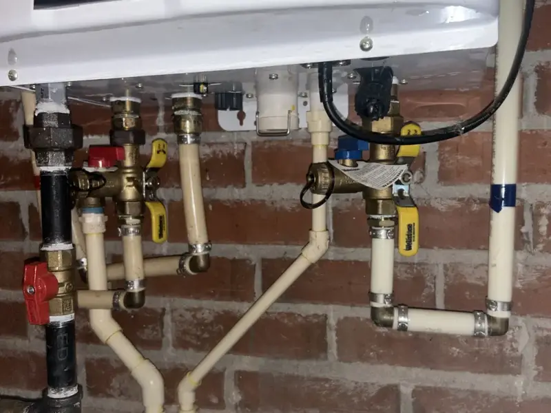 Neatly piped gas, water and condensate lines under a Navien tankless water heater